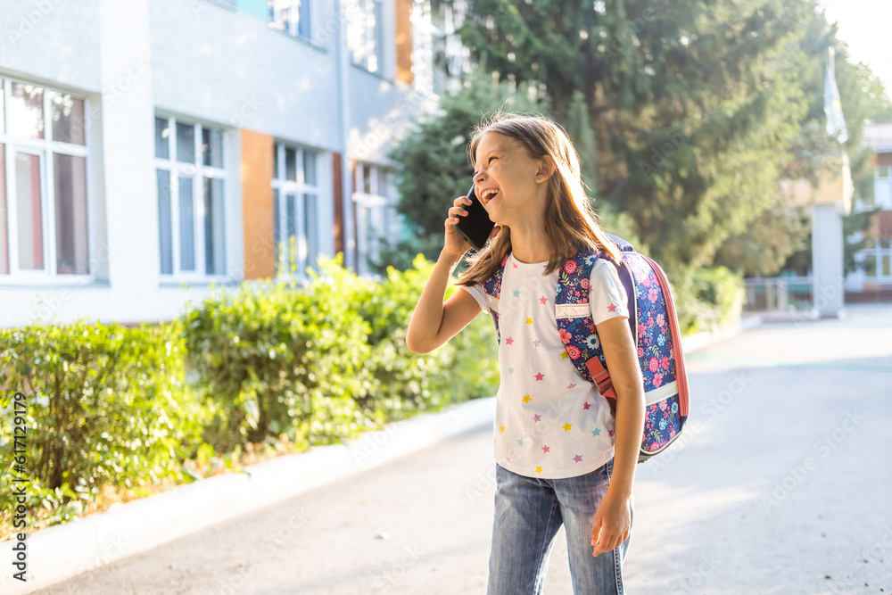 Cute school girl with backpack using smartphone