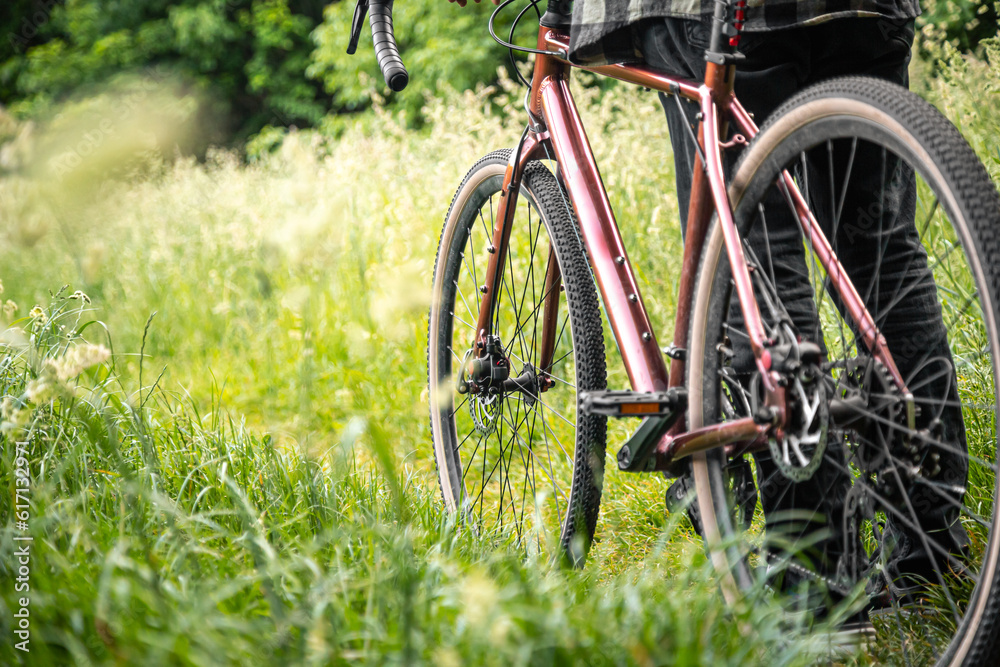 A man with a bicycle in the forest among the grass.