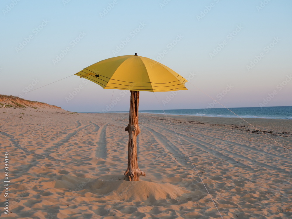 A yellow beach umbrella on the shore of le Cap Ferret during the sunset. June 26th, 2023, France.