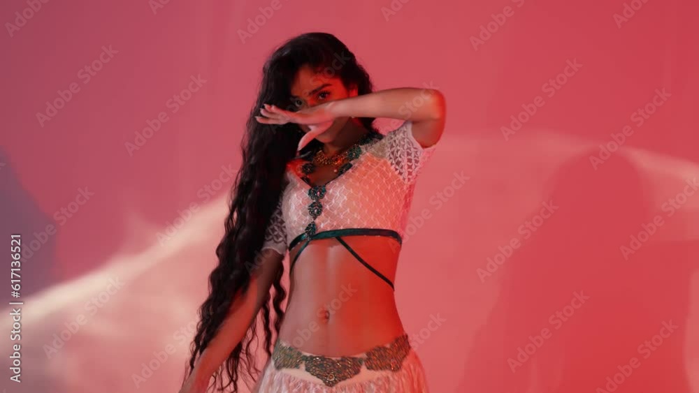Beautiful woman dancing oriental dance on red background with light effects