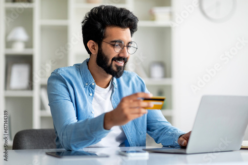 Online Payments Concept. Handsome Indian Man Using Laptop And Credit Card