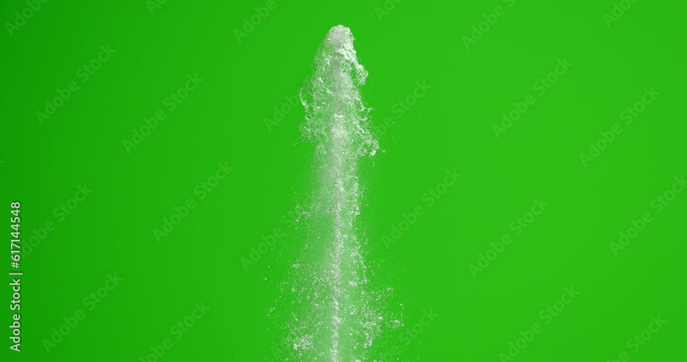 The stream of water hits the top with force. Splashes of water on a green background. The fountain rises.
