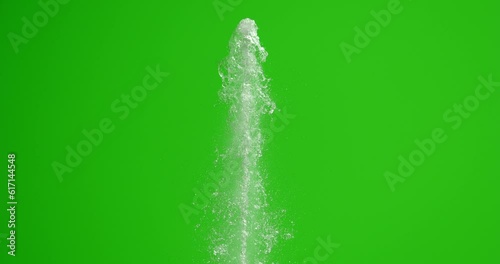 The stream of water hits the top with force. Splashes of water on a green background. The fountain rises.
