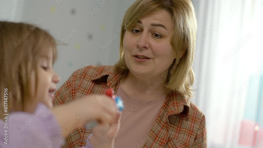 A girl with a teacher performs exercises on learning colors in kindergarten. The development of thinking and logic in a child during class and preparation for school. High quality 4k footage A girl with a teacher performs exercises on learning colors in kindergarten. The development of thinking and logic in a child during class and preparation for school. High quality 4k footage