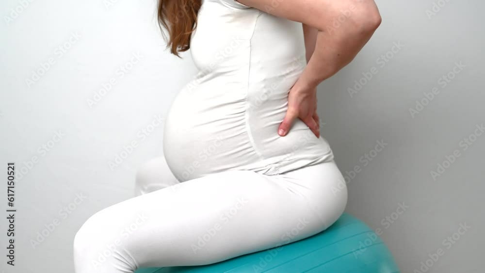 Midsection of heavily pregnant baby bump held by hands of woman