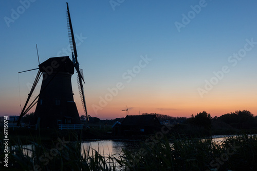 Beautiful wooden windmills at sunset in the Dutch village of Kinderdijk. Windmills run on the wind. The beautiful Dutch canals are filled with water. Beautiful sunset.