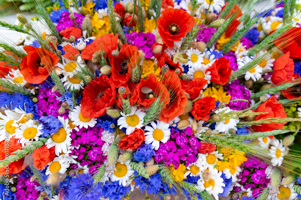 Large bouquet of summer wildflowers with poppies, daisies and cornflowers garnished with wheat ears closeup.  Spring flower background.