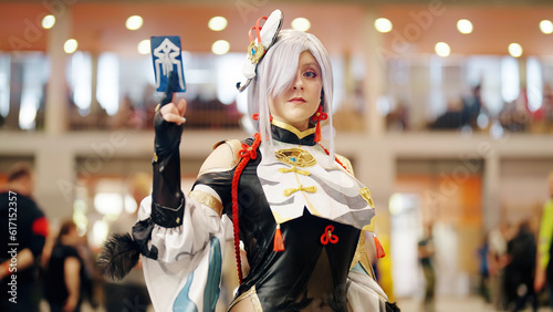 Anime Girl With Gray Hair In Battle Outfit Cosplay Holding Card At The Anime Convention
