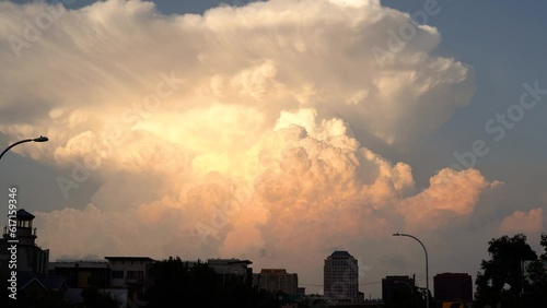 Giant thunderstorm cloud in sunset with city in foreground