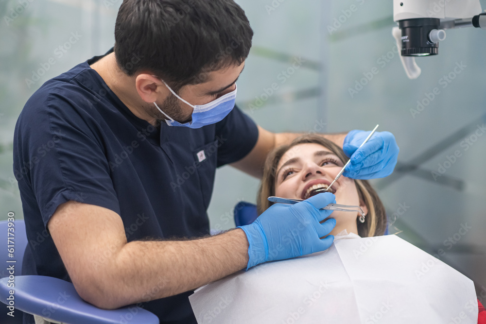 Dental care in modern clinic focused orthodontist looking at teeth of female patient using professional tools skilled specialist preparing woman for bite correction Dental care in modern clinic focused orthodontist looking at teeth of female patient using professional tools skilled specialist preparing woman for bite correction