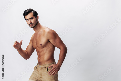 Male fashion model with a naked torso and abs packs sporty runs on a white isolated background, fashionable clothing style, copy space, space for text