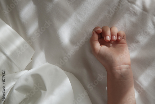 Child's hand on cotton whte sheet. Children's nap time or bedtime. 