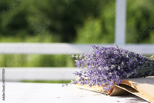 Lavender bouquet laid over an old book on a white wooden table. Vintage style. Photo with empty place for the text