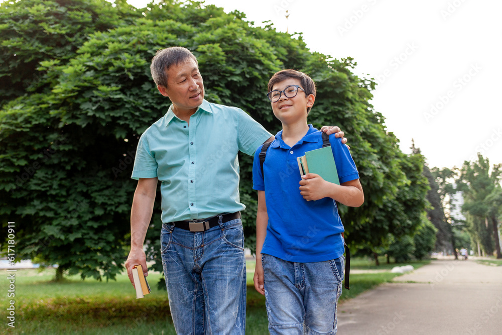 asian old father goes to school with son and carry books, korean boy with backpack and glasses goes to school asian old father goes to school with son and carry books, korean boy with backpack and glasses goes to school