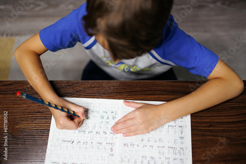 Kid siting on table doing Chinese homework photo