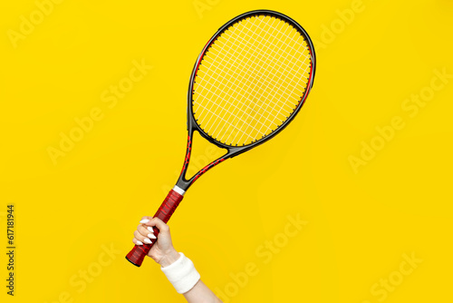 female hand holds tennis racket on yellow isolated background, sports equipment, close-up © Богдан Маліцький