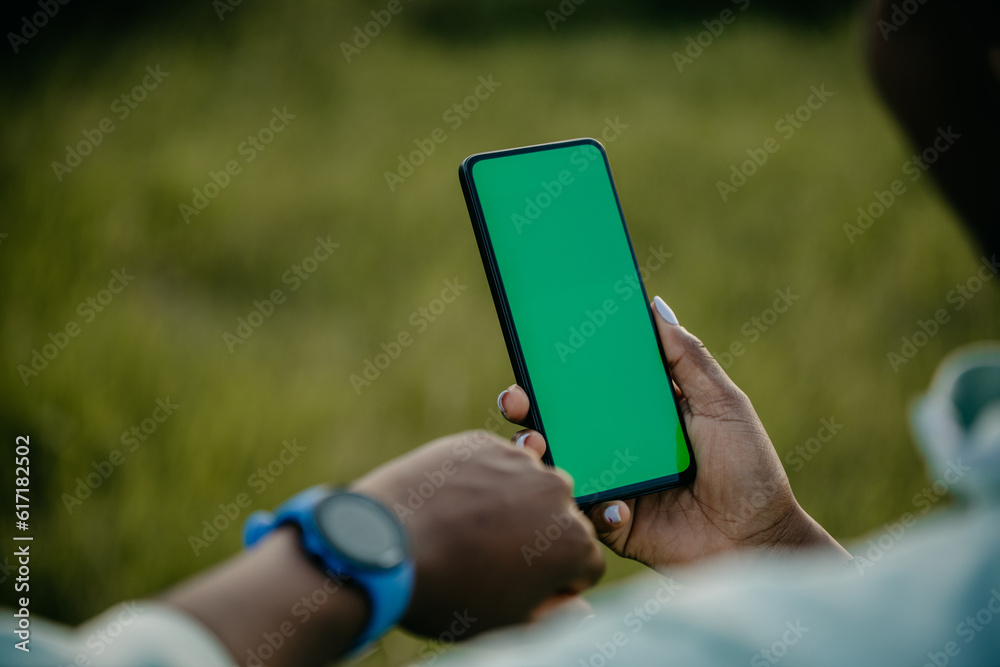 Fitness Tracking in Motion: a black jogger effortlessly glides along a forest path while her smartwatch monitors her heart rate and distance covered on her phone.