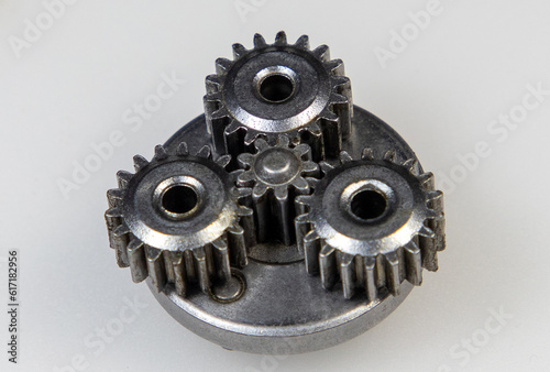 A close-up with a metallic planetary gear set on a white background