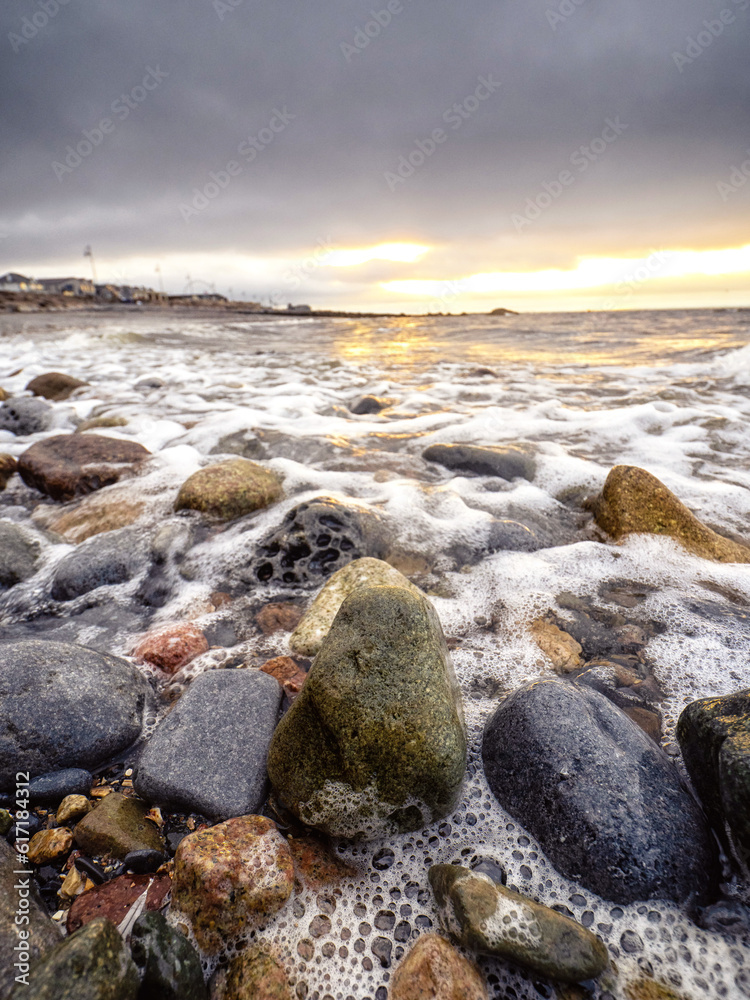 Rough stone beach by Blackrock diving tower in Salthill, Galway city, Ireland. Dark cloudy sky before sunrise. Calm nature scene. Selective focus. Rough stone beach by Blackrock diving tower in Salthill, Galway city, Ireland. Dark cloudy sky before sunrise. Calm nature scene. Selective focus.