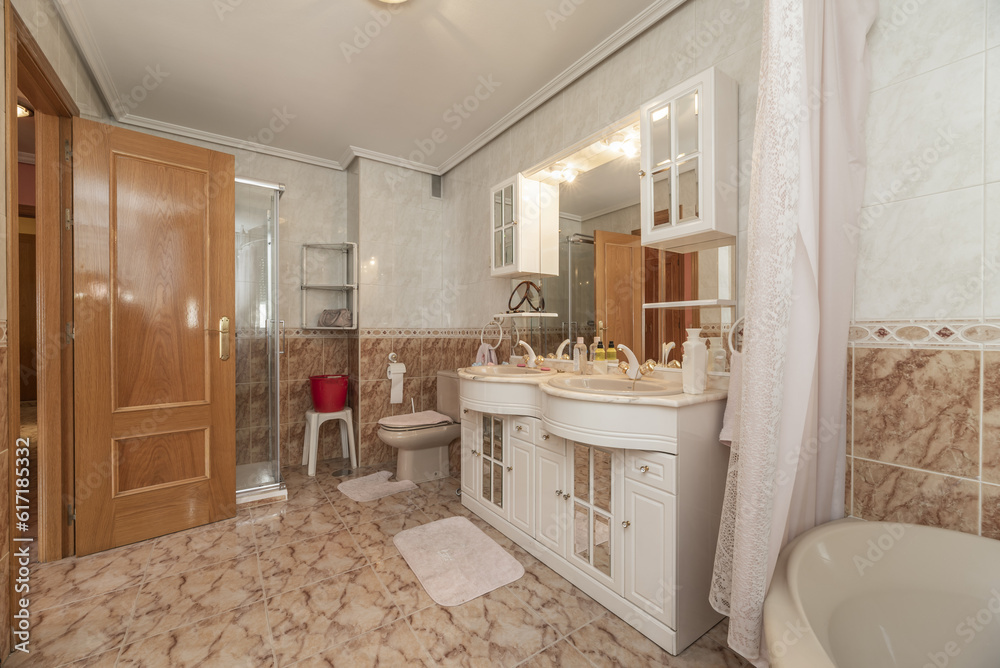 Conventional toilet with white wooden furniture with two porcelain bowls embedded in the marble countertop