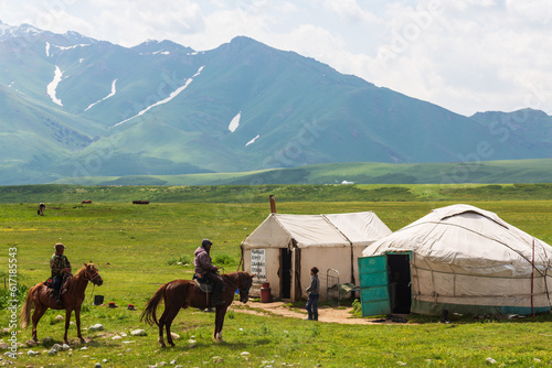 Ala Bel pass, Kyrgyzstan - 15 June 2022: Kyrgyz Yurts and other summer dwellings in the mountains. Local people and a horseman. Ala Bel pass, Bishkek Osh highway in Kyrgyzstan photo