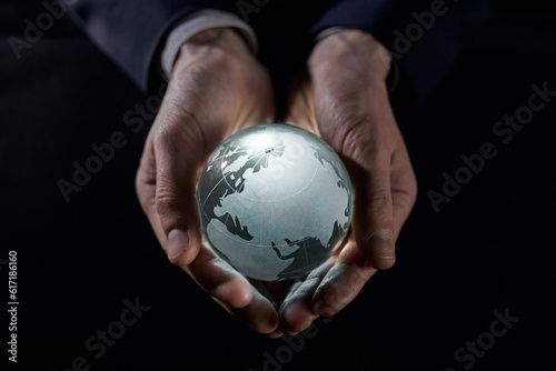 A man holds a glowing globe in his hands. close-up on a black background