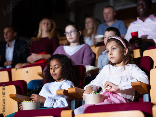 little female viewer sitting at premiere in cinema