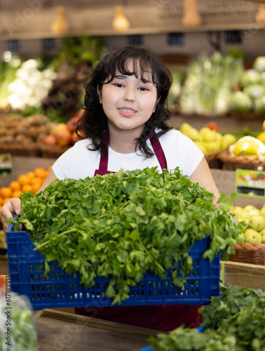 Portrait of friendly smiling female employee of a grocery supermarket with parsley © JackF