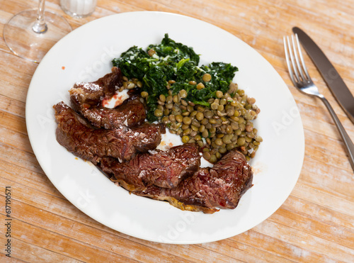 Tasty portion of roasted beef with lentils and spinach served beautifully on plate