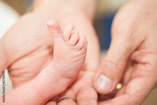 Closeup of a newborn foot and her father hands at hospital on the day of her birth © anamejia18