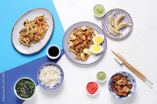 Composition with tasty Chinese dishes and chopsticks on light background