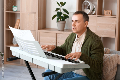 Mature man playing synthesi...