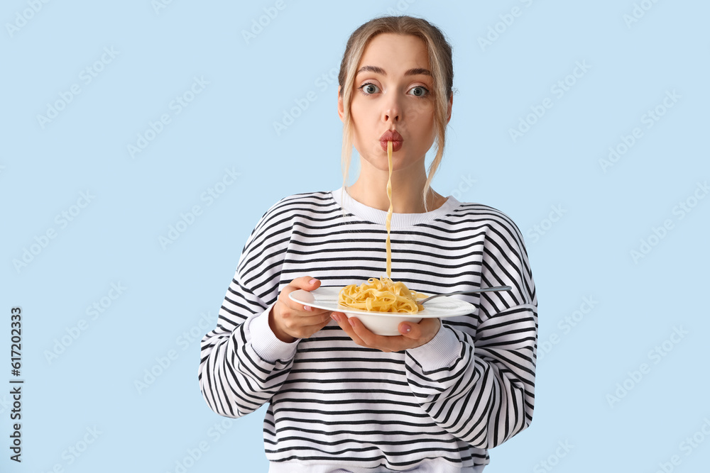 Young woman eating tasty pasta on blue background Young woman eating tasty pasta on blue background