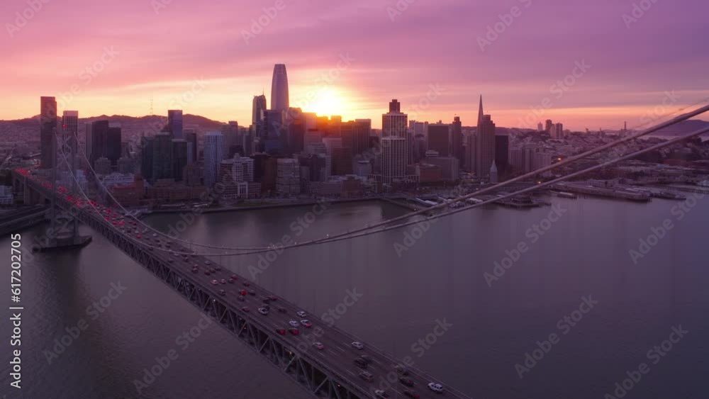 San Francisco at dusk with beautiful pink clouds in sky at golden sunset. Traffic at Bay Bridge in direction of city. Epic cityscape view with skyscraper buildings.Scenic establishing shot of downtown San Francisco at dusk with beautiful pink clouds in sky at golden sunset. Traffic at Bay Bridge in direction of city. Epic cityscape view with skyscraper buildings.Scenic establishing shot of downtown