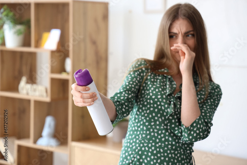 Foto Displeased young woman with air freshener at home