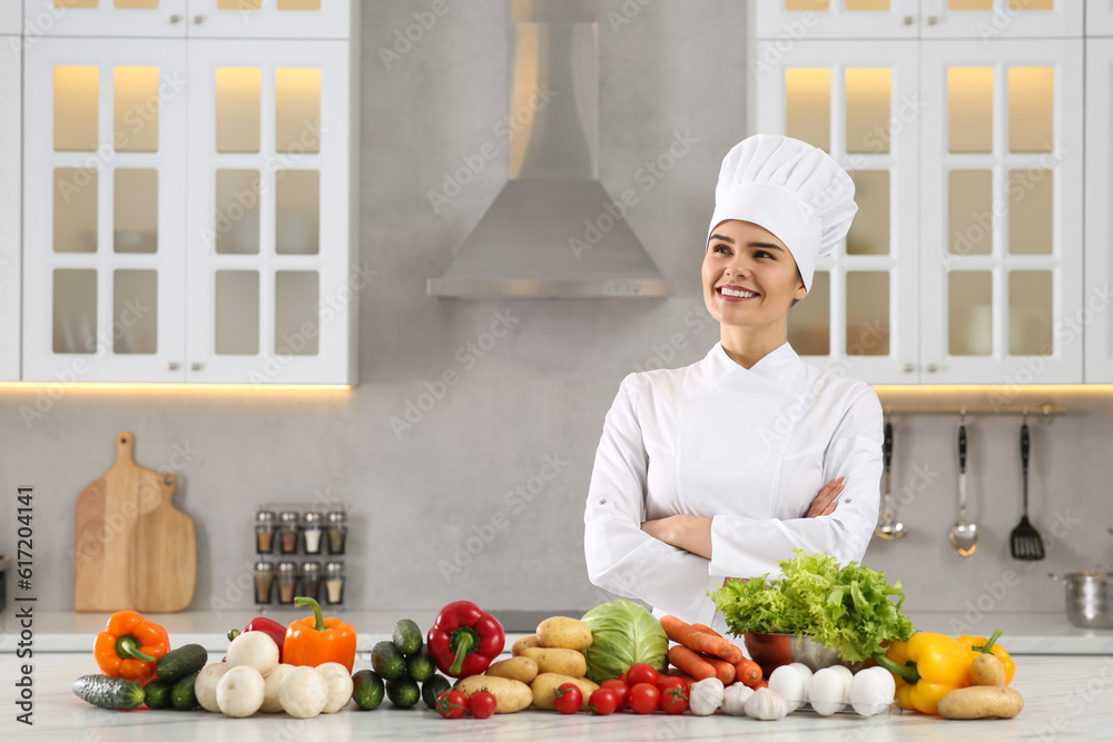 Happy chef near fresh vegetables at table in kitchen. Space for text Happy chef near fresh vegetables at table in kitchen. Space for text