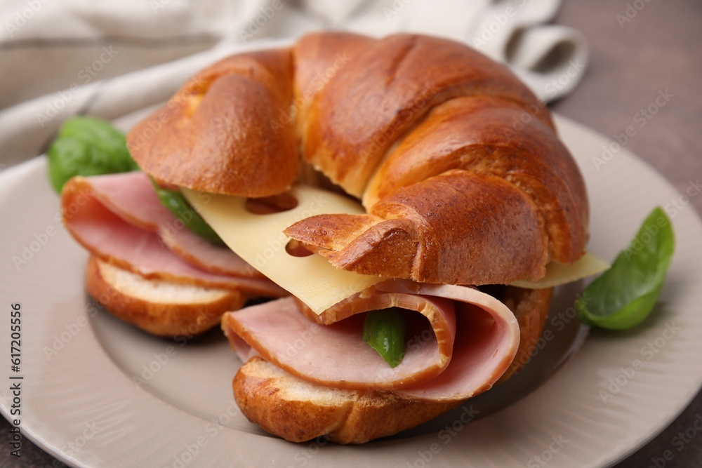 Tasty crescent roll with ham, cheese and basil on plate, closeup Tasty crescent roll with ham, cheese and basil on plate, closeup