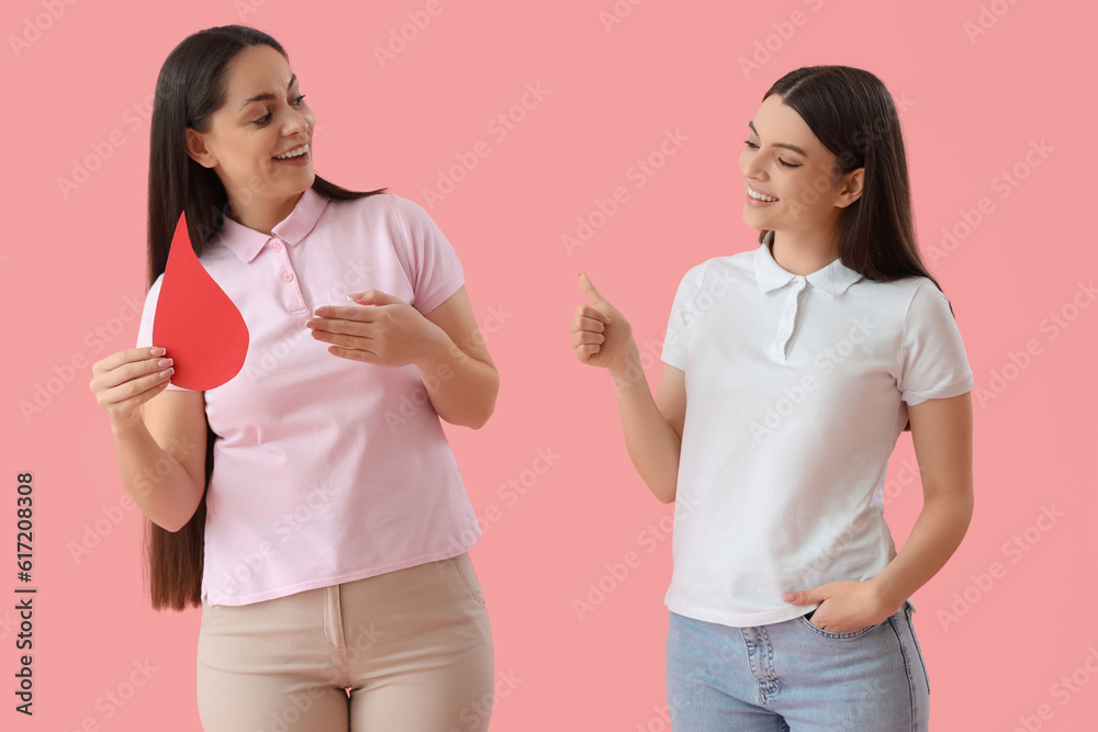 Female donors with paper blood drop on pink background Female donors with paper blood drop on pink background