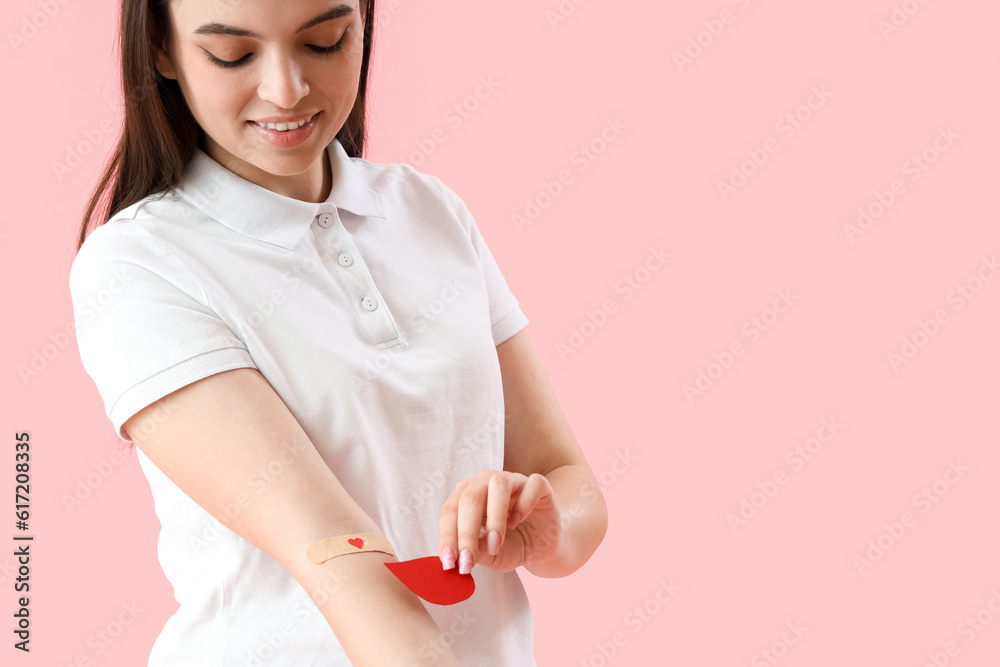 Female donor with applied medical patch and paper blood drop on pink background Female donor with applied medical patch and paper blood drop on pink background