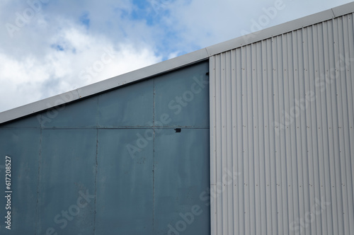 Teal and Gray Warehouse with Blue and White Sky Above.