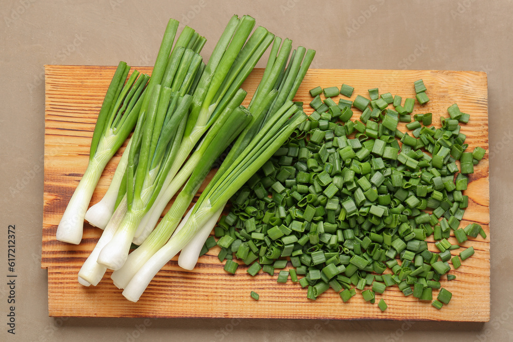 Board with slices of fresh green onion on brown background Board with slices of fresh green onion on brown background