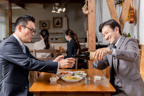 飲み会・接待・親睦会で上司や同僚にお酌する笑顔のビジネスマン 