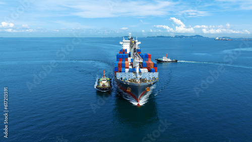 Aerial front view of cargo ship carrying container and running with tug boat for import export goods from cargo yard port to custom ocean concept freight shipping by ship .
