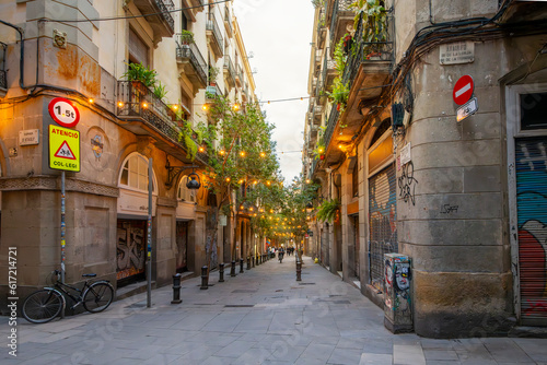 Canvas Print A narrow alley through a picturesque section of the Gothic Quarter with lights illuminated the street at twilight in Barcelona, Spain