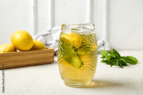Glass of ice tea and wooden box with lemons on white background