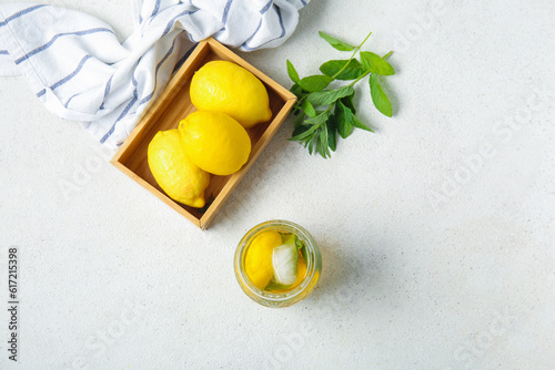 Glass of ice tea and wooden box with lemons on white background