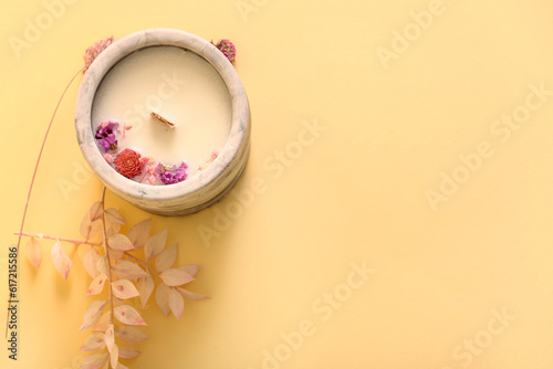 Holder with candle and flowers on beige background