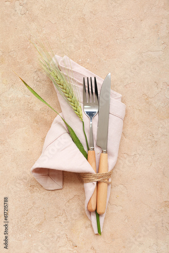 Cutlery and spikelet tied in napkin on brown grunge table
