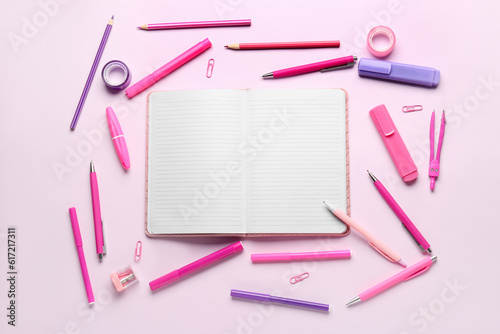 Notebook with different school stationery on lilac background