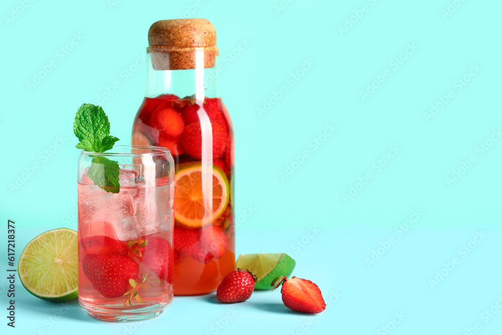 Glass and bottle of infused water with strawberry on blue background Glass and bottle of infused water with strawberry on blue background